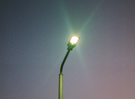 A low-angle shot captures a solitary street lamp against an evening sky. 