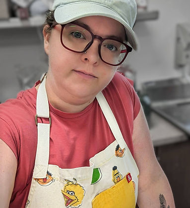 Chef/Owner Cara (white woman mid 30s brown hair) in Sesame Street apron