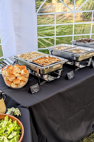 catered wedding buffet with salad, rolls, and 3 chafing dishes