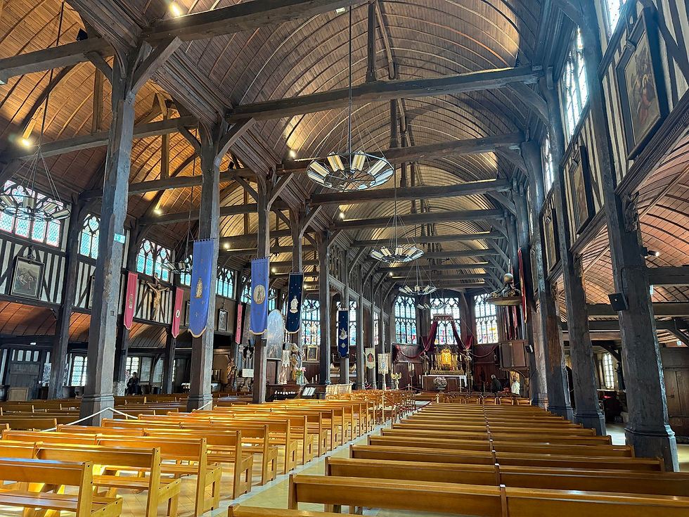 Wooden church interior with empty pews, banners hanging from beams, stained glass windows, and high arched ceiling creating a serene atmosphere.
