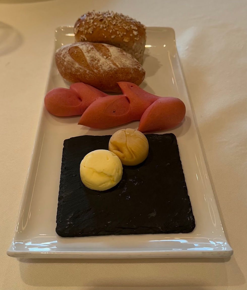 Complimentary rolls, two circles of butter and a beetroot roll and a seeded roll.