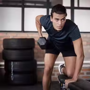 Homem realizando exercício na academia com halteres 