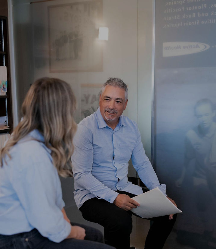 Chiropractor Dr. Dan Migliarese speaking with patient in Calgary clinic