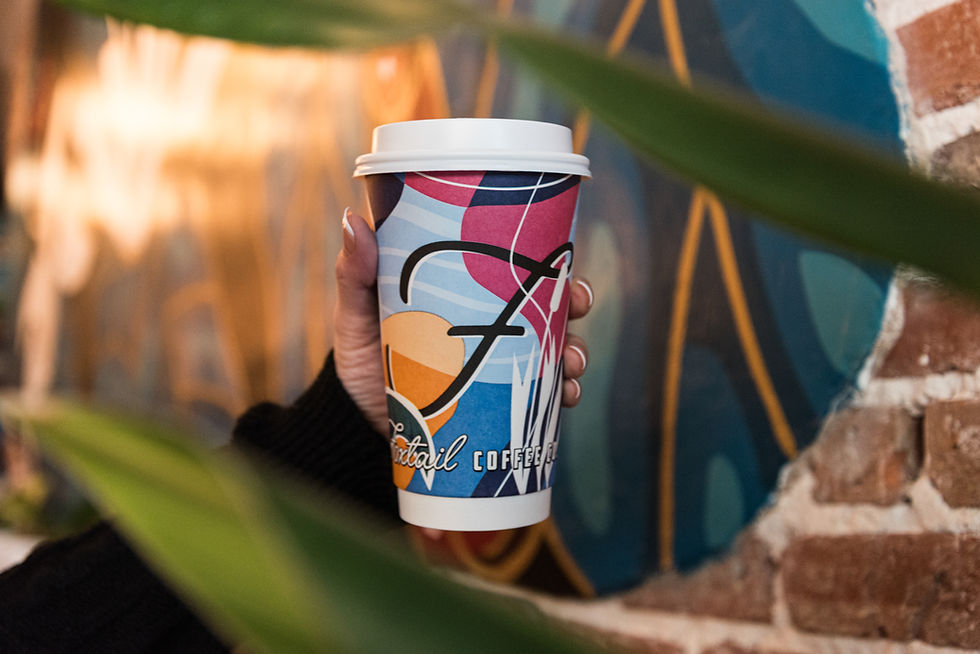 A hand holding a Foxtail coffee branded hot coffee cup in at the Foxtail location in Mount Dora, FL .
