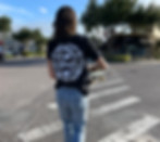 Swine & Sons team member is overlooking a crosswalk from behind, holding a skateboard. 