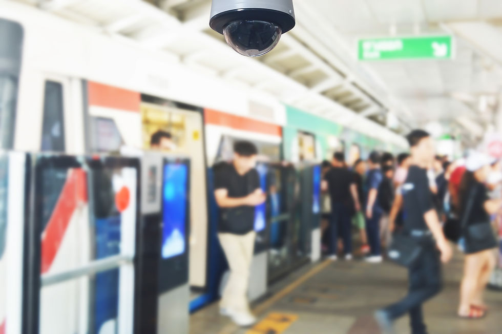 Busy public platform with security surveillance camera in sharp focus in foreground