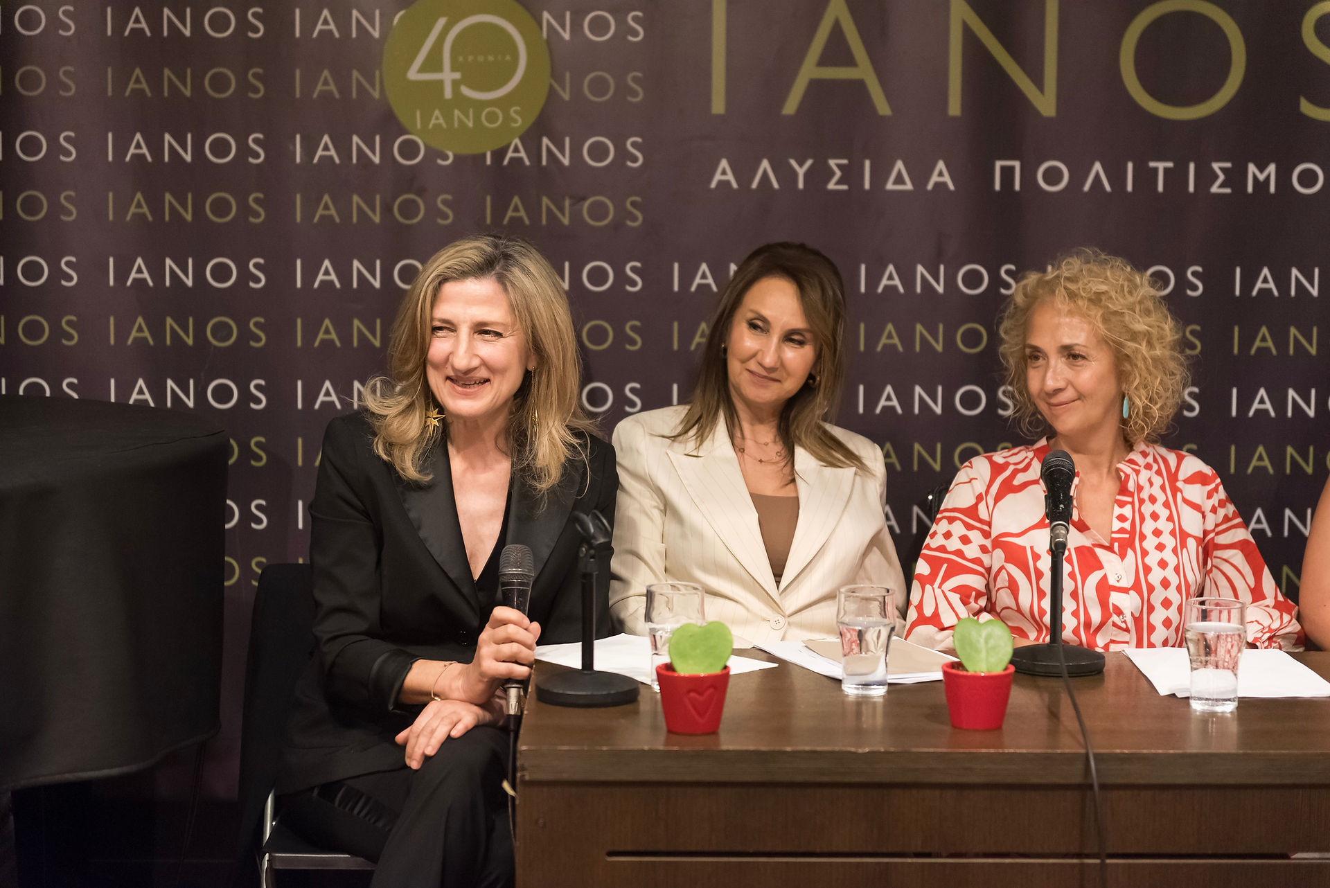 Christina Charokopou sitting next to her friends and fellow alumnae guest speakers, thanking them and the audience at the presentation event of her Concept Book titled "APHRODITE REINVENTED® - Η ΑΦΡΟΔΙΤΗ ΠΟΥ ΕΠΑΝΕΦΗΥΡΑ" at IANOS Bookstore Athens, June 2nd, 2026