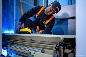 Arbeider voert onderhoud en herstelling uit aan een liftinstallatie.