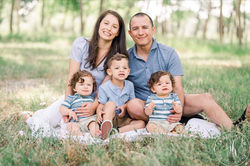 A family of five sitting together outdoors in a grassy area.