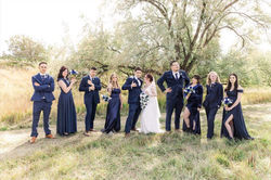 A wedding party including the bride and groom with bridesmaids in blue dresses and groomsmen in dark
