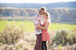 Couple embracing outdoors with a blurred mountain backdrop.