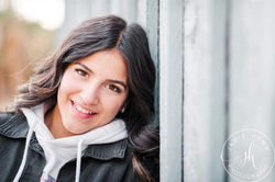 A close-up portrait of a young woman with long dark hair smiling.
