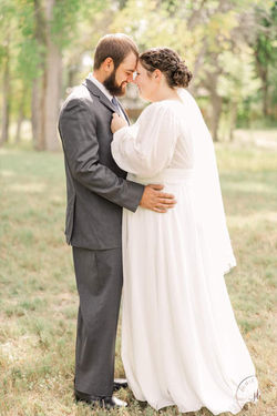A bride and groom embracing closely outdoors.