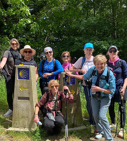 Retreat group of women smiling beside Camino de Santiago trail markers.