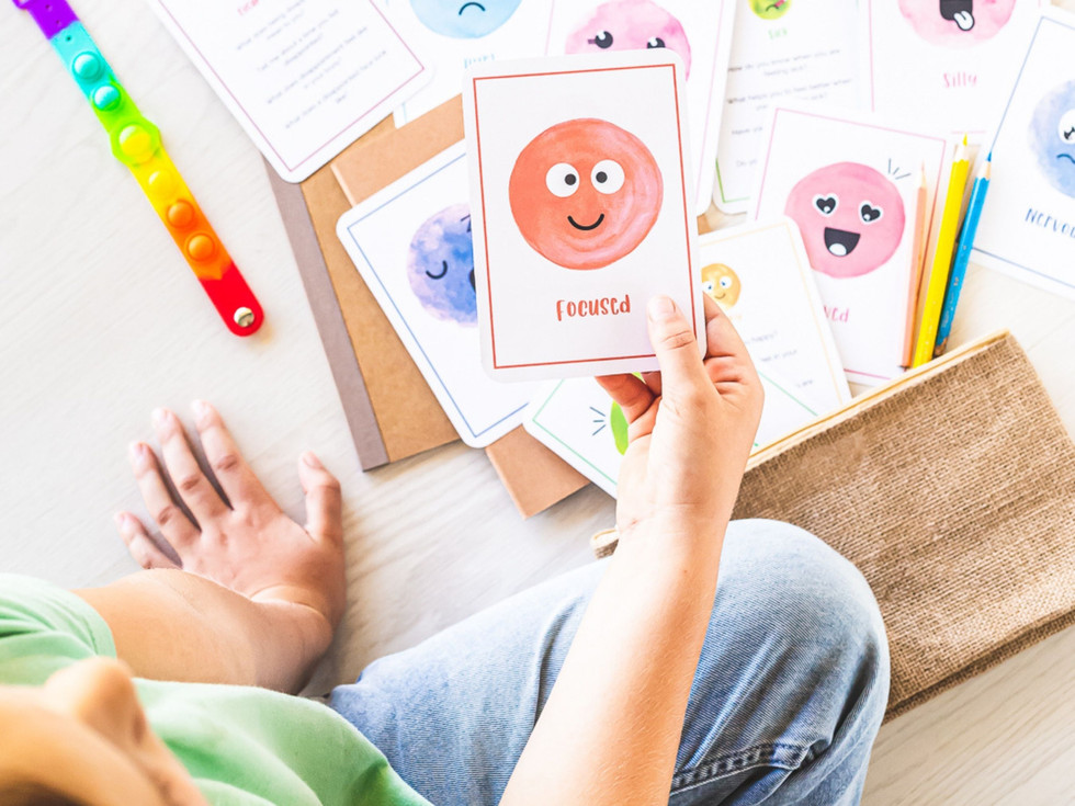 Child holds 'Joyful' emotion flashcard for emotional regulation