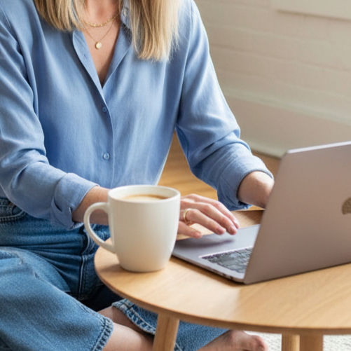 Person typing on a laptop with a coffee mug