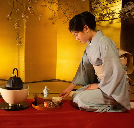 Japanese woman demonstrating a traditional tea ceremony to LGBTQ+ travelers.