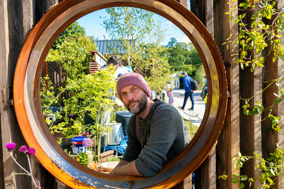 a man wearing a pink hat is looking through a round window