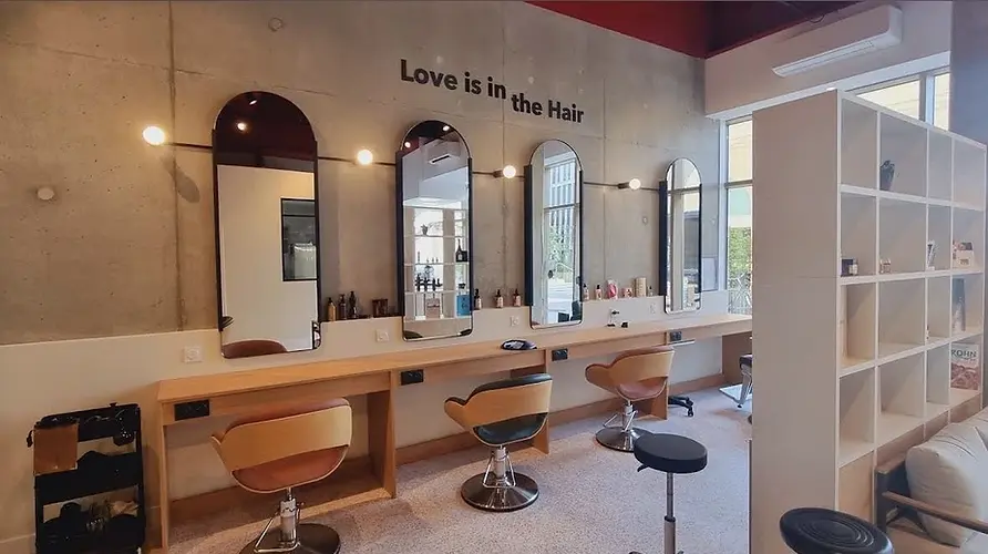 Photo du salon de coiffure Une Bouchée d'Hair. On y voit des miroirs et des fauteuils de coiffeur