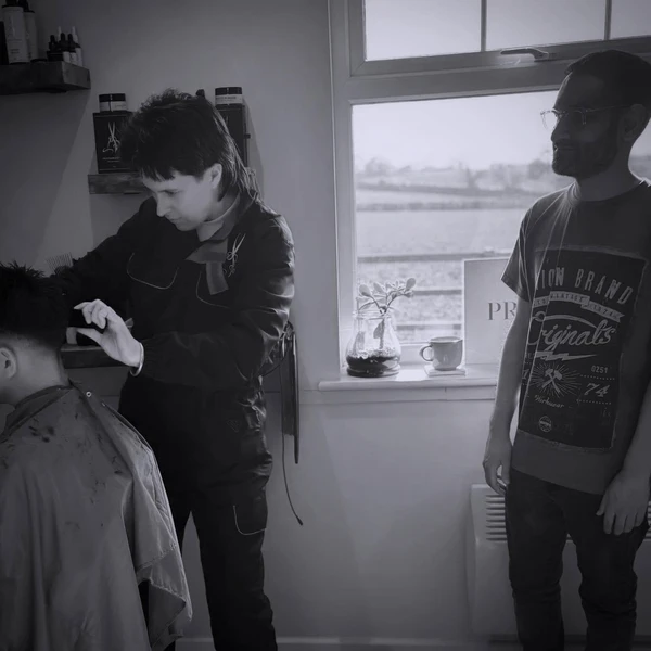 student learning scissor work from barbering teacher