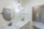 Hall bathroom features two sinks and designer selected lighting and tile
