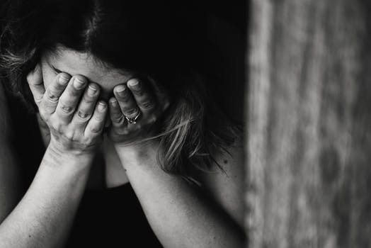 A woman grieving into her hands covering her face, black and white