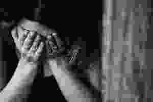 A woman grieving into her hands covering her face, black and white