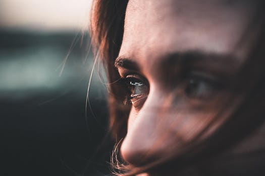 Woman's partially shielded face with eyes showing signs of emotion