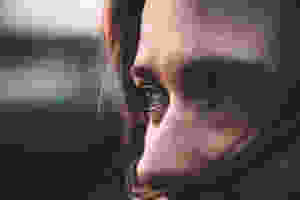 Woman's partially shielded face with eyes showing signs of emotion