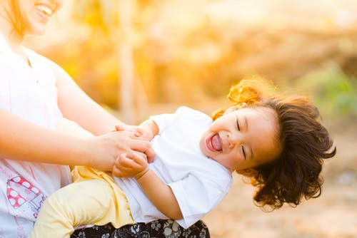 Smiling child being played with by a woman