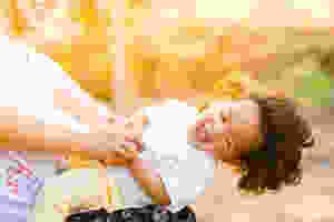 Smiling child being played with by a woman