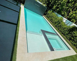 Beautifully done pool and spa with grey coping finish and white plaster, with a Baja and steps.