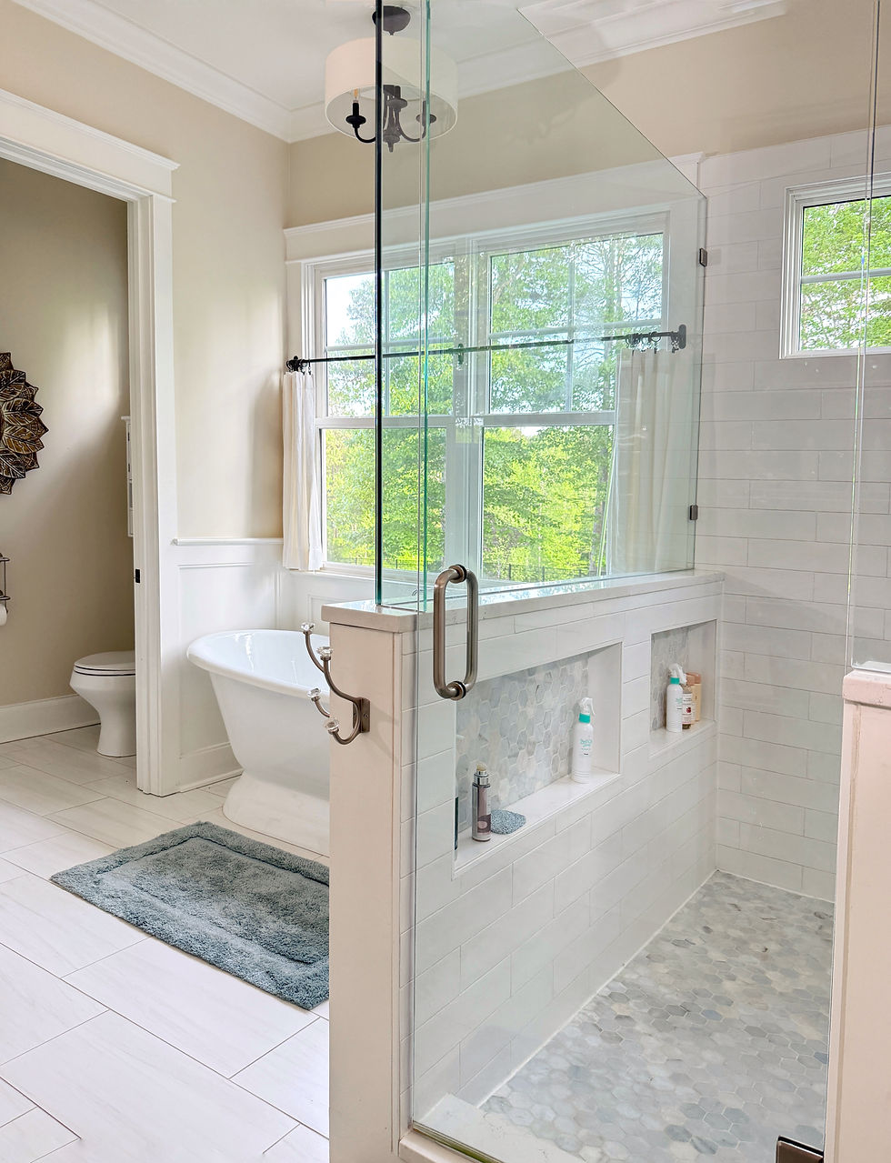 Bright timeless bathroom featuring small hex mosaic tile on the shower floor paired with large format floor tile throughout the main bathroom, combining practical shower drainage, slip resistance, and classic bathroom design