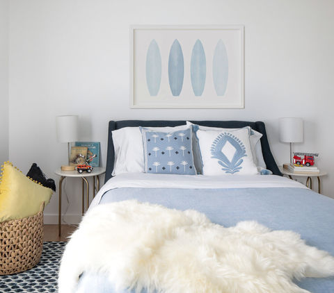 Children's room with blue bedding and white fur throw.