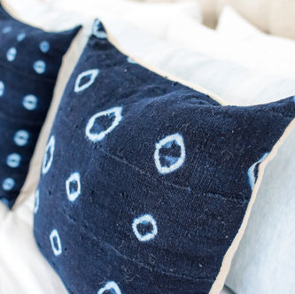 Close-up of navy blue and white pillows on bed.