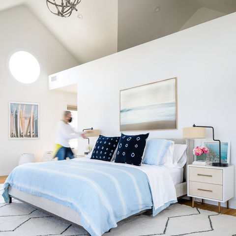 Bedroom with light blue bedding and modern chandelier.