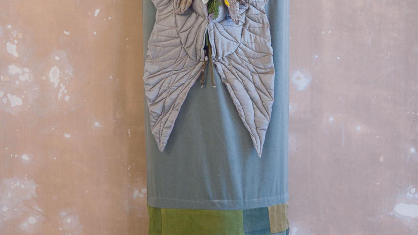 Full-length view of the Sage Wings artisan burial shroud with decorative textile wings and seasonal foliage