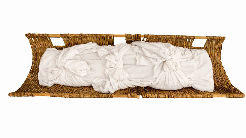 Simple white linen burial shroud secured on a willow stretcher