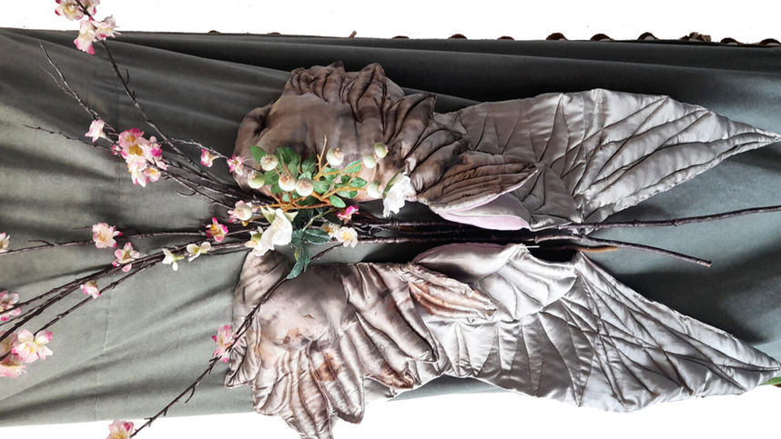 Close-up of hand-crafted textile wings and floral arrangement on the Sage Wings burial shroud.