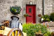 Milk churn on old cart in front of red barn door
