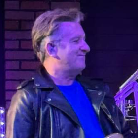 Man with light hair in a leather jacket smiling