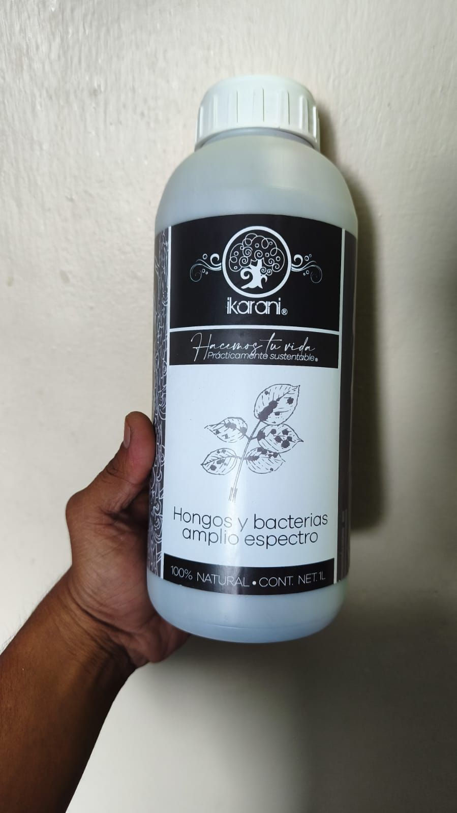 Mano sosteniendo envase de fungicida para hongos y bacterias.