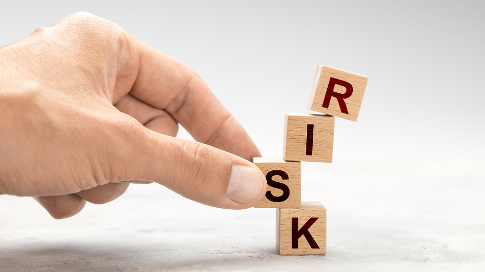Hand balancing wooden blocks spelling "RISK" against a light gray background, creating a sense of stability and caution.