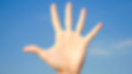 Hand with fingers spread against clear blue sky, no text. Bright, open, and cheerful mood.