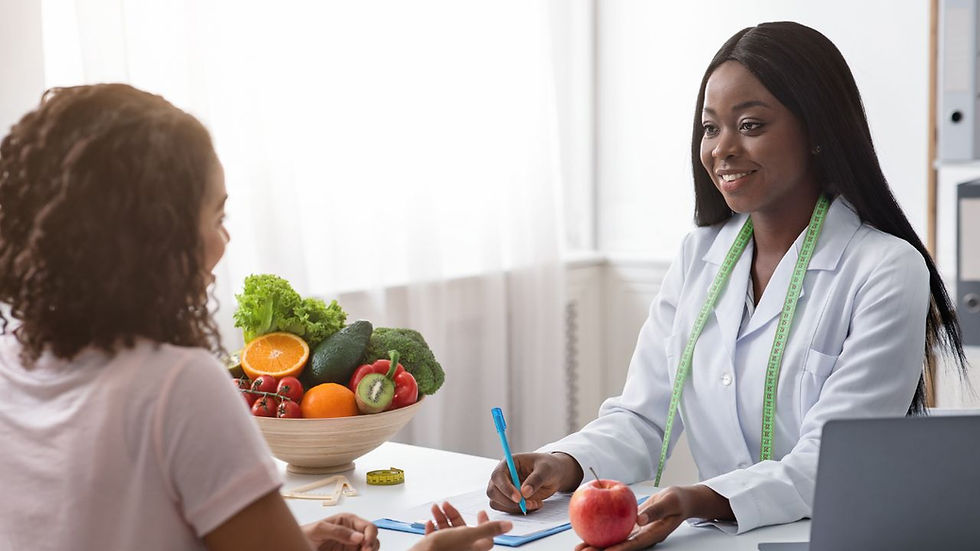 Nutritionist with tape measure advises a woman, holding an apple, at a desk with fresh fruits and veggies in a bright office.