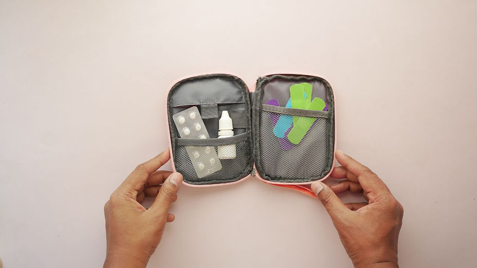 Hands hold an open first aid kit with pills, an eyedropper bottle, and colorful band-aids inside. The background is a soft pink.