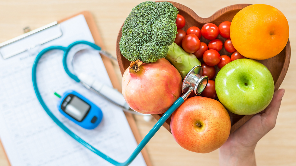 Heart-shaped bowl with broccoli, apples, orange, and tomatoes, next to a stethoscope and glucose meter on a clipboard. Healthy living mood.