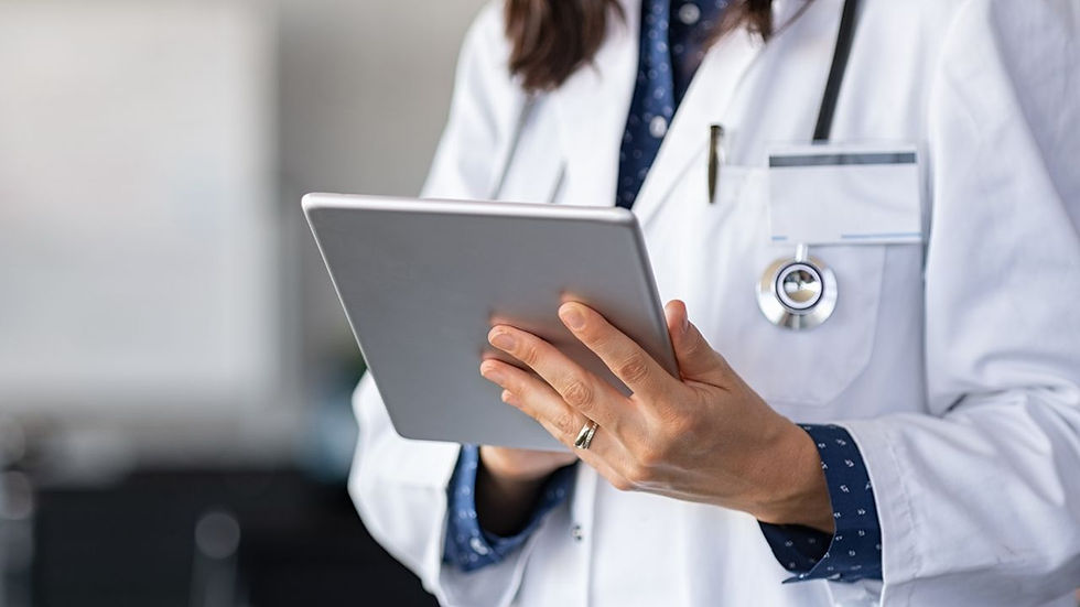 Doctor in white coat holding a tablet, with stethoscope visible. Background is blurred, creating a focused and professional atmosphere.