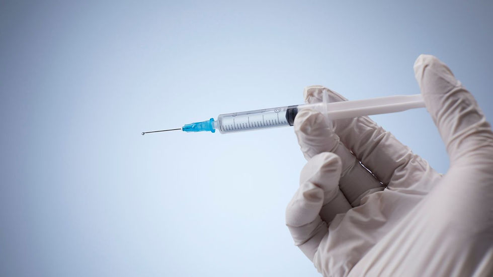 Gloved hand holding a syringe with a blue tip against a light blue background, conveying a clinical and sterile environment.