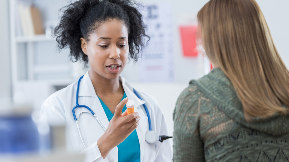 Doctor in white coat discusses medication with a patient in a green sweater. Medical setting, calm atmosphere. Stethoscope visible.